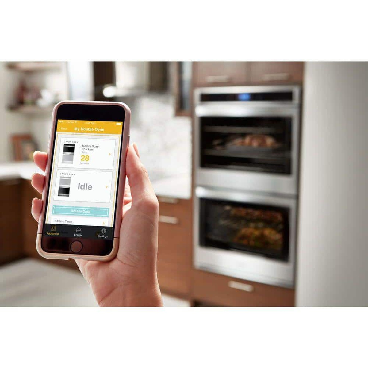 Smartphone controlling the Whirlpool double wall oven via the connected app in a modern kitchen.