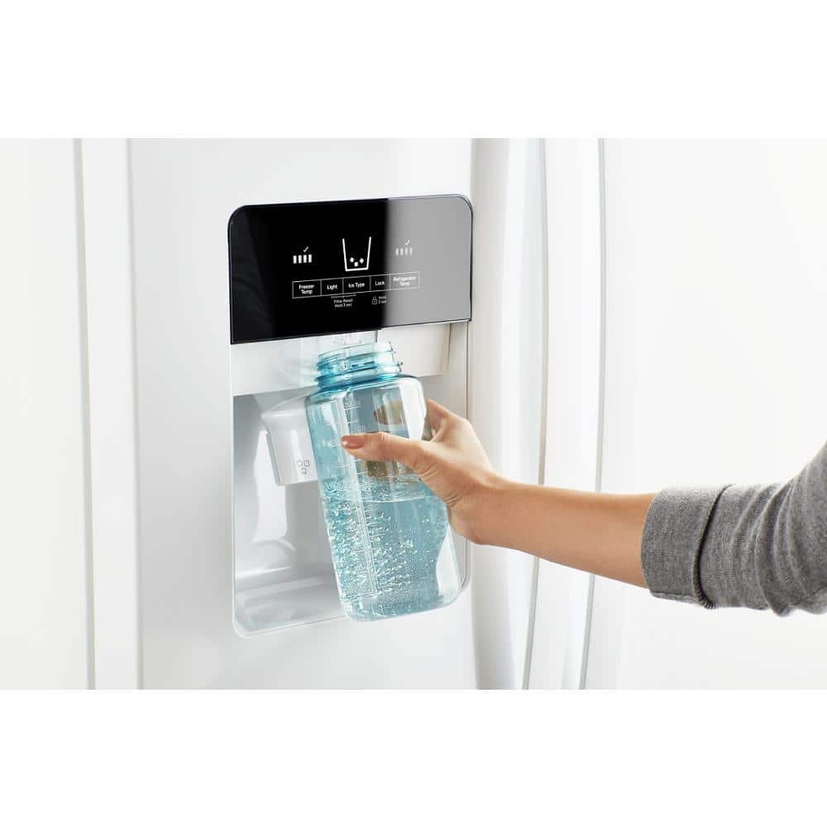 Hand filling a water bottle at the refrigerator’s exterior ice and water dispenser with touch controls.