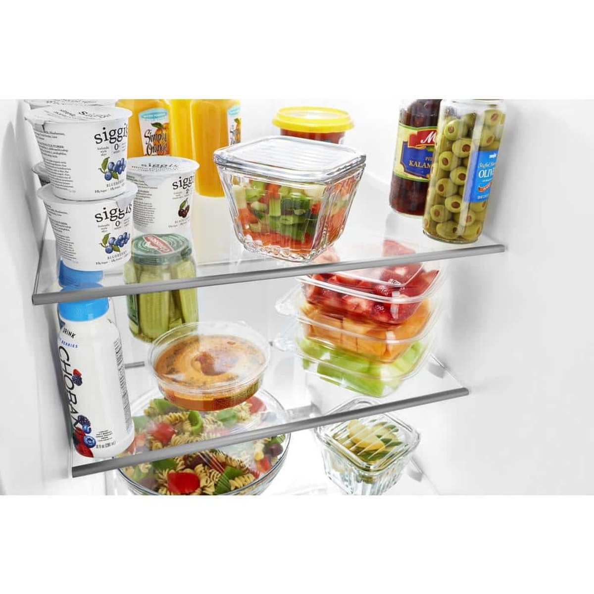 Close-up of frameless glass refrigerator shelves holding bowls and containers of food.