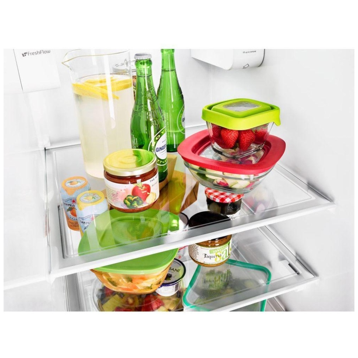 Close view of frameless glass shelves holding beverages and bowls inside refrigerator.
