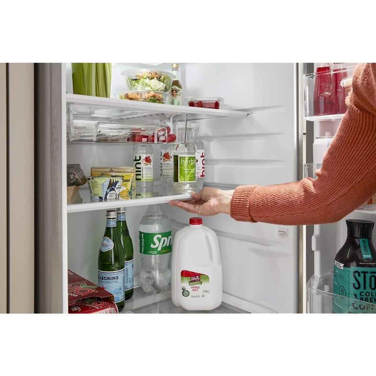 Hand sliding the Flexi-Slide bin under a glass shelf to make room for tall items.