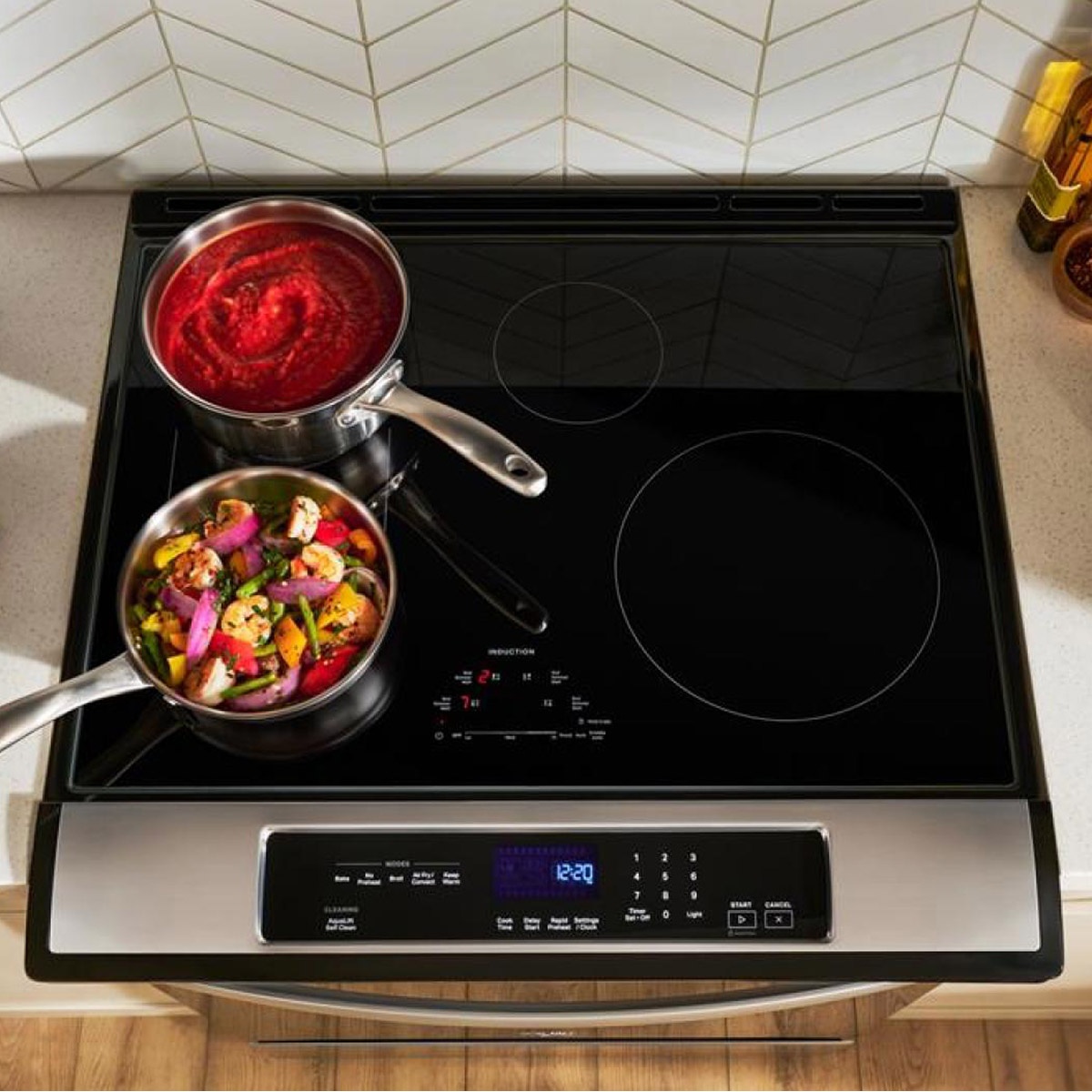 Top view of Whirlpool induction cooktop with two pans simmering and sautéing.