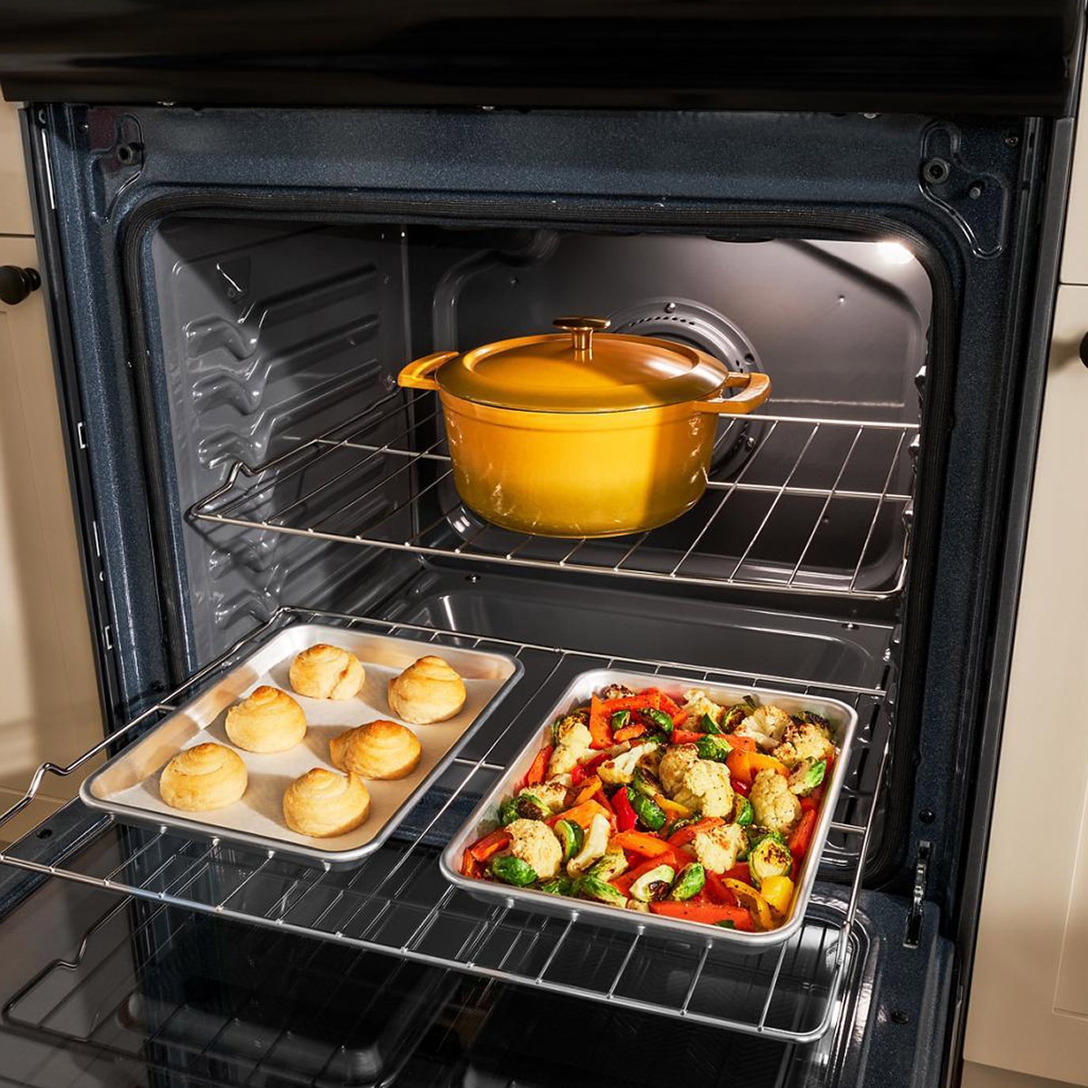 Oven interior loaded with Dutch oven and trays of vegetables and pastries illustrating convection airflow.