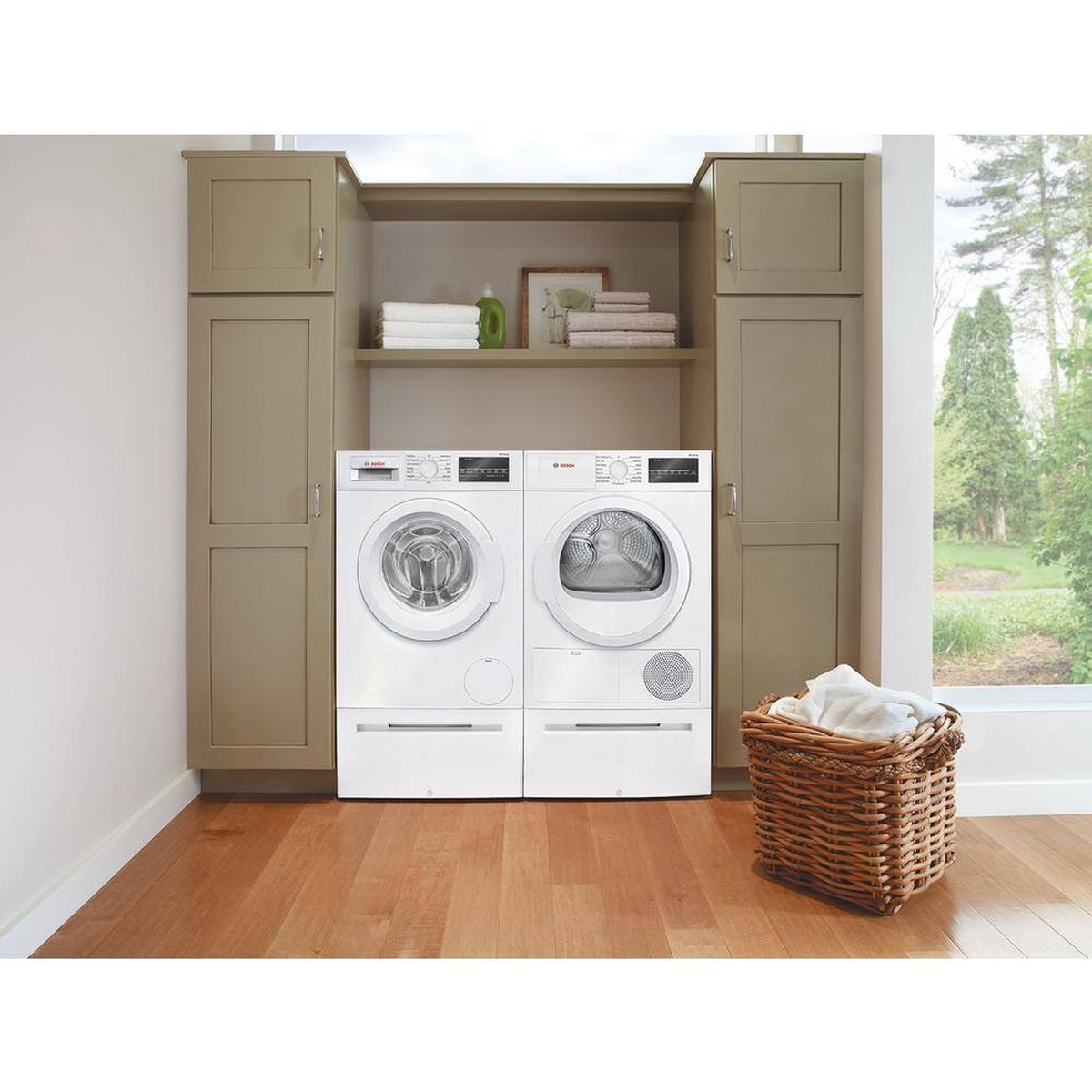 Bosch washer and dryer on matching white pedestals in a built-in laundry nook