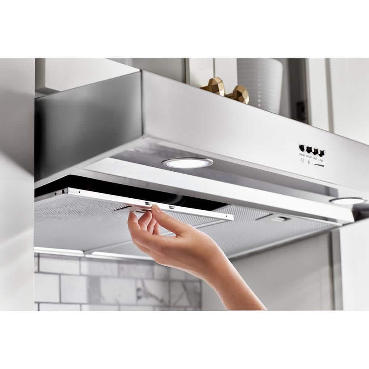 Hand removing dishwasher-safe grease filter from Whirlpool under-cabinet hood