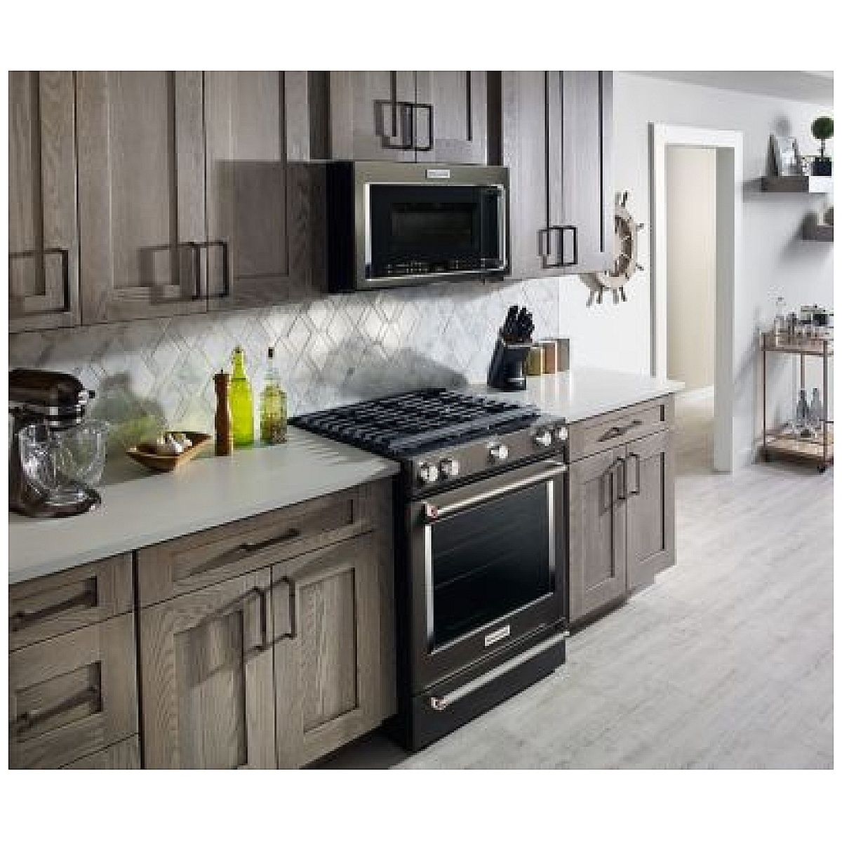 Microwave installed above a gas range in a bright kitchen, showing workspace beneath.