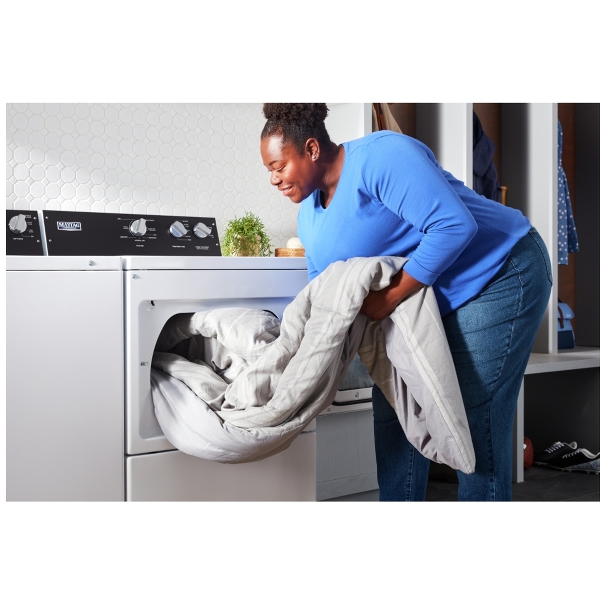 Person loading a bulky comforter into the dryer.