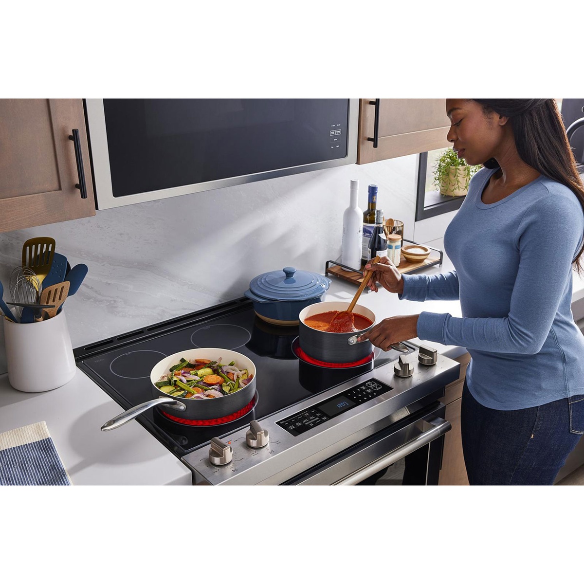 Smooth cooktop in use with multiple pans and glowing elements