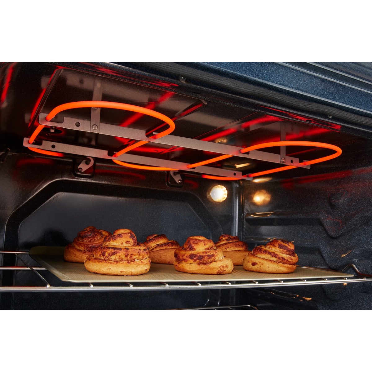 Close-up of the oven broil element glowing above pastries on a rack.
