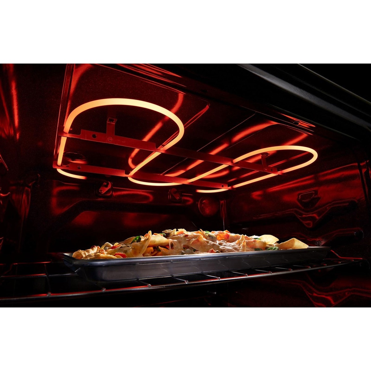 Inside oven view of broil element glowing above food on a baking sheet.