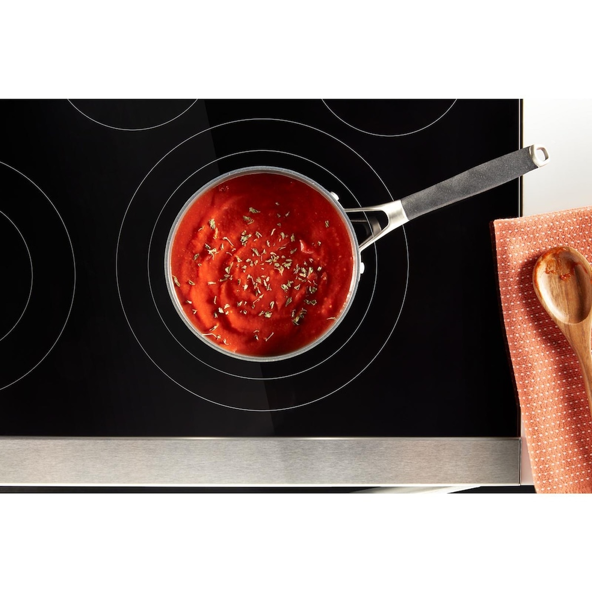 Edge-to-edge glass cooktop with simmering sauce on an element