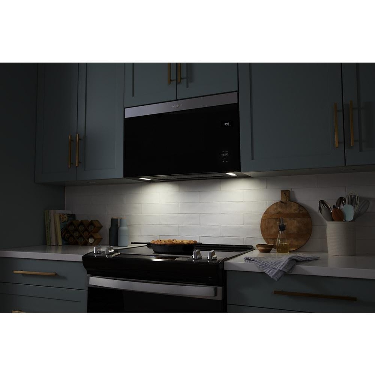 Microwave installed over range with bright underside cooktop lights on
