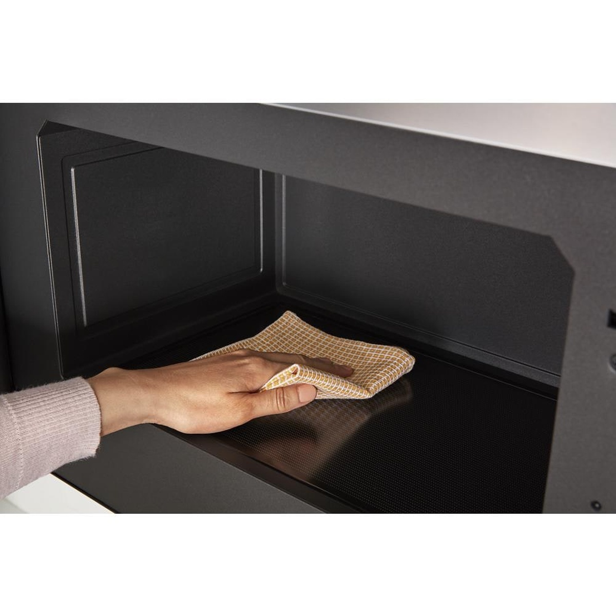 Flat, turntable-free microwave interior being wiped clean