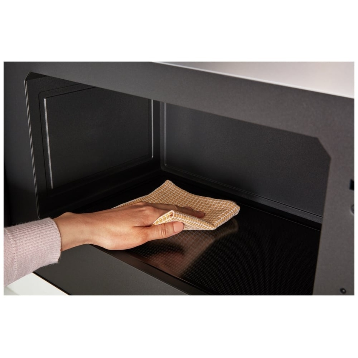Hand wiping the flat interior of the microwave