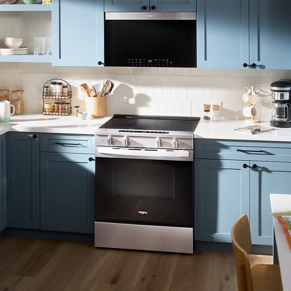 Whirlpool slide-in electric range installed in a modern kitchen with blue cabinets