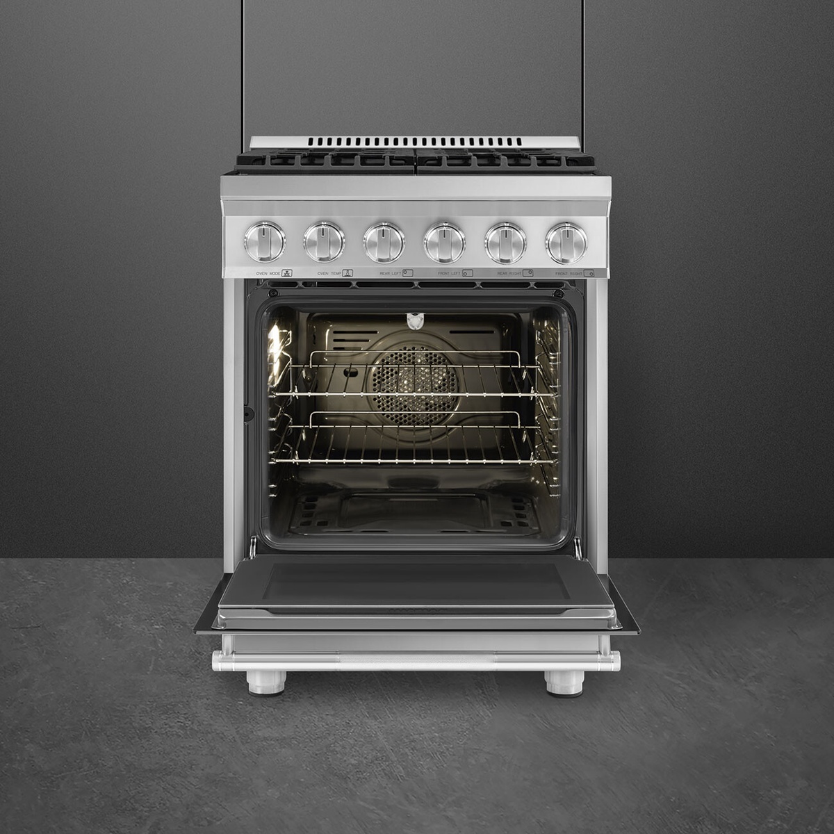 Front view of the Smeg 24-inch stainless steel range with the oven door open, showing multiple rack positions and the rear fan cover