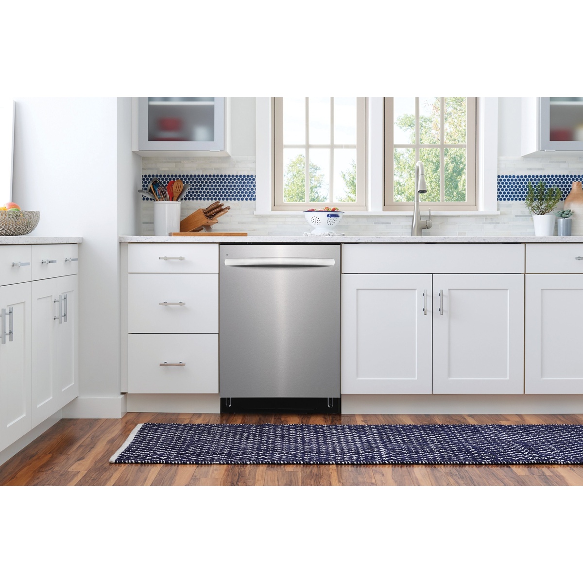 Stainless steel Frigidaire dishwasher installed between white kitchen cabinets