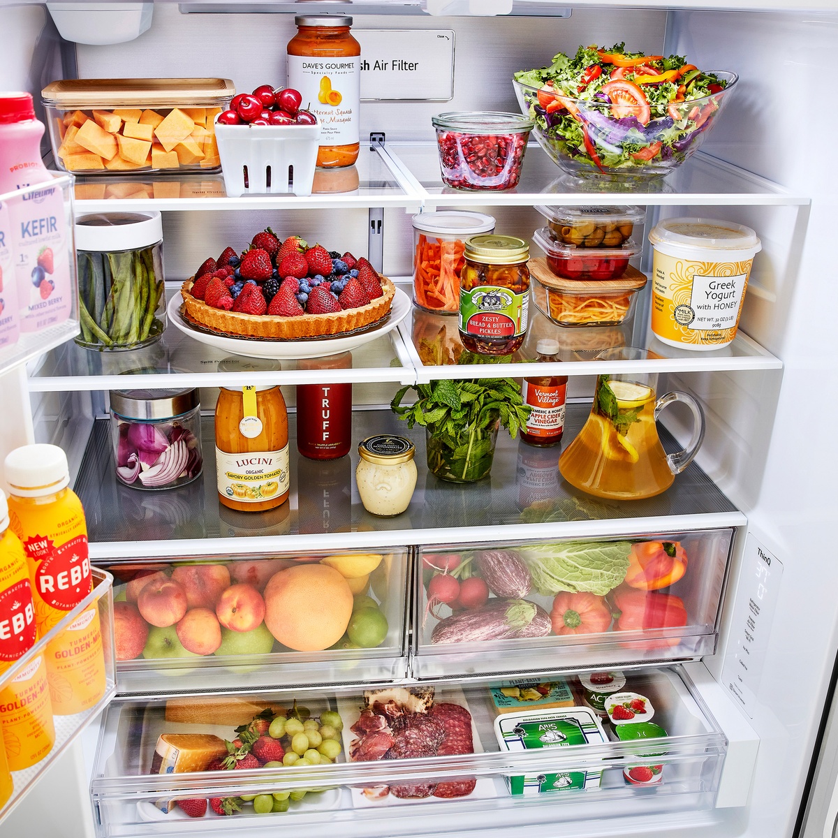 Interior of the LG refrigerator showing glass shelves, door bins, crisper drawers, a full-width drawer, and a Fresh Air Filter panel