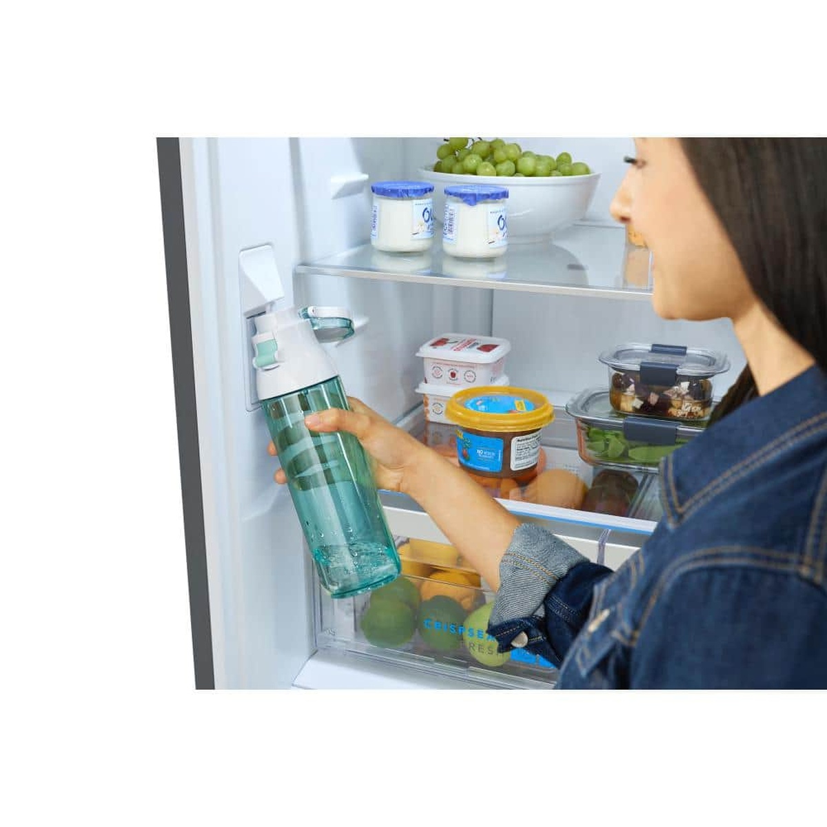 Person filling a water bottle from the refrigerator’s internal water dispenser inside the fresh-food compartment