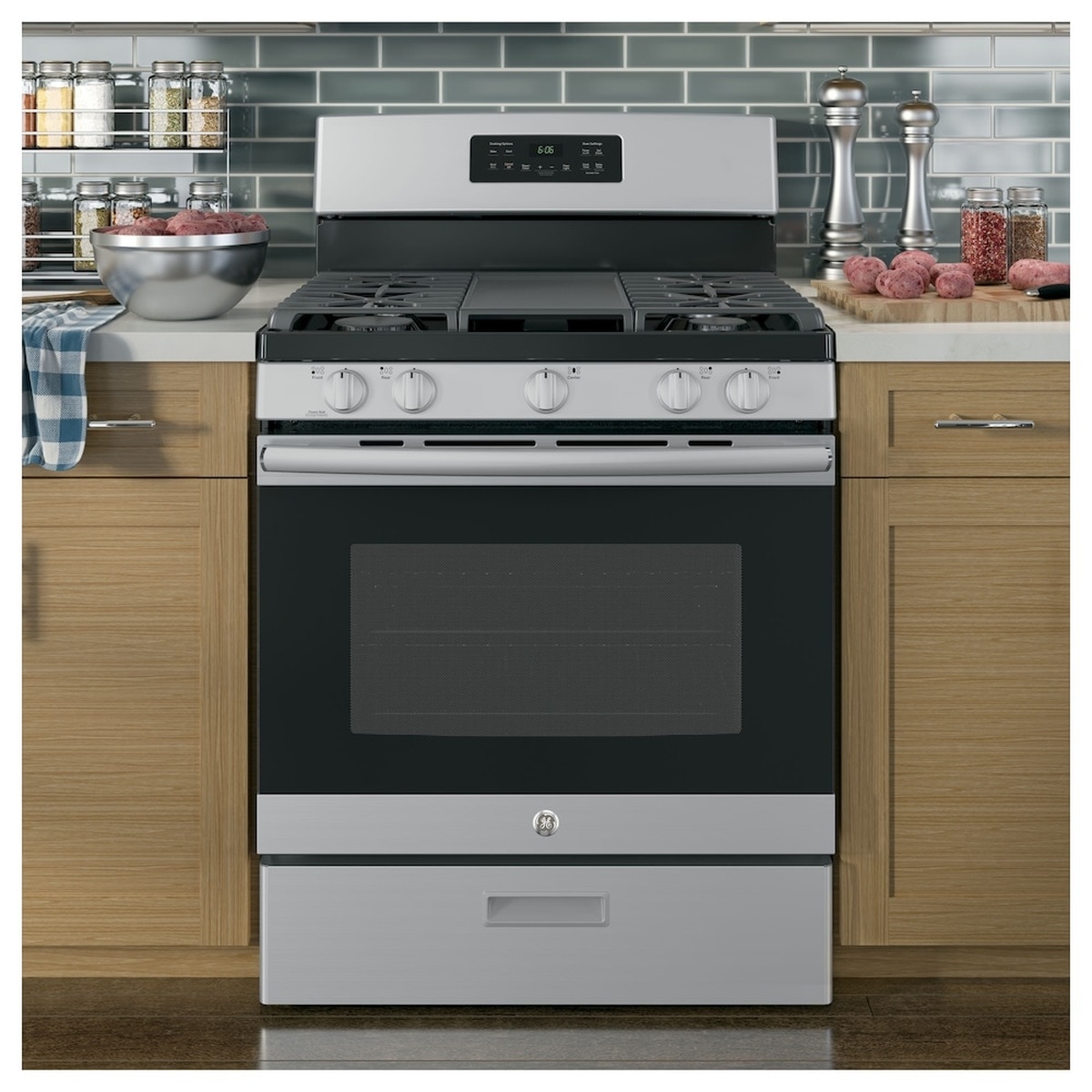 GE stainless steel freestanding gas range installed between kitchen cabinets