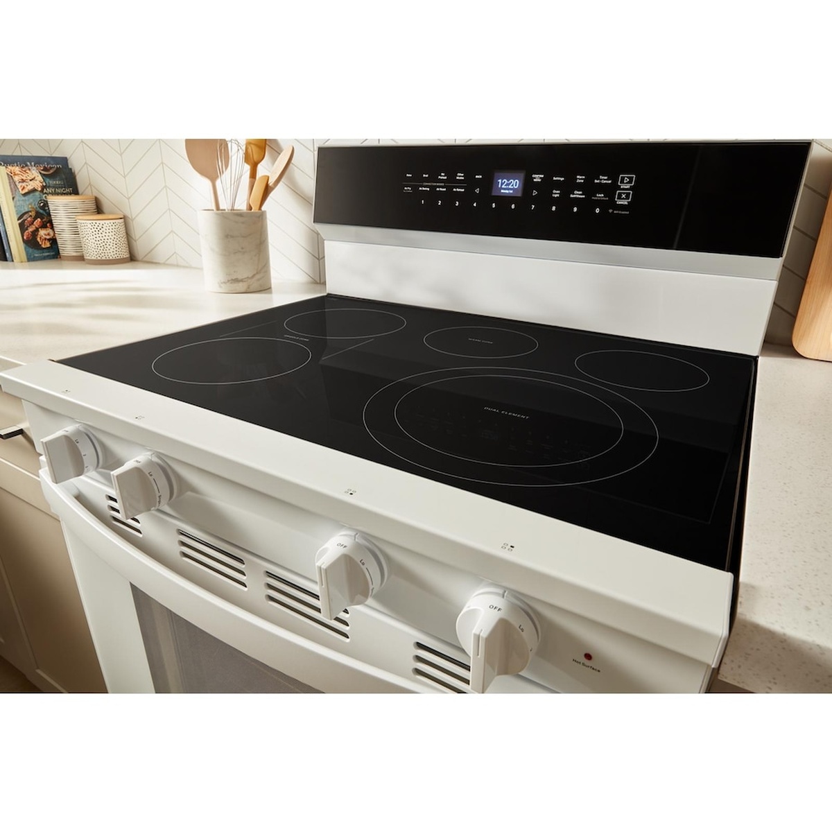 White Whirlpool freestanding electric range installed in a kitchen, showing the smooth cooktop and back control panel