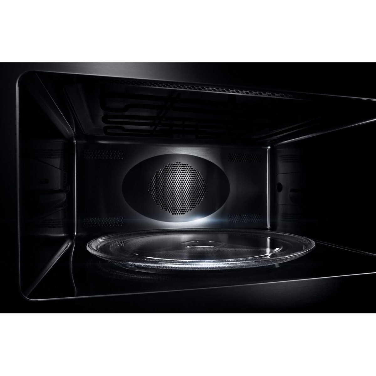 Interior of the speed oven showing stainless steel walls, rear venting, and a glass turntable