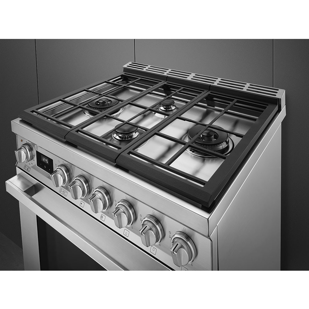 Angled view of the stainless range cooktop showing four gas burners, continuous cast iron grates, and front control knobs with a central digital display