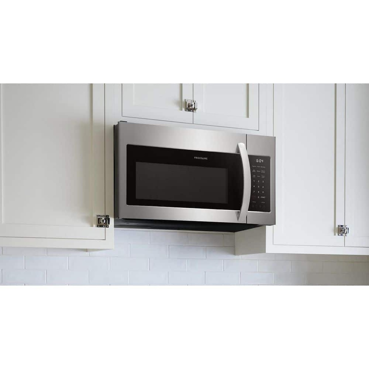 Stainless steel Frigidaire over-the-range microwave installed between white kitchen cabinets