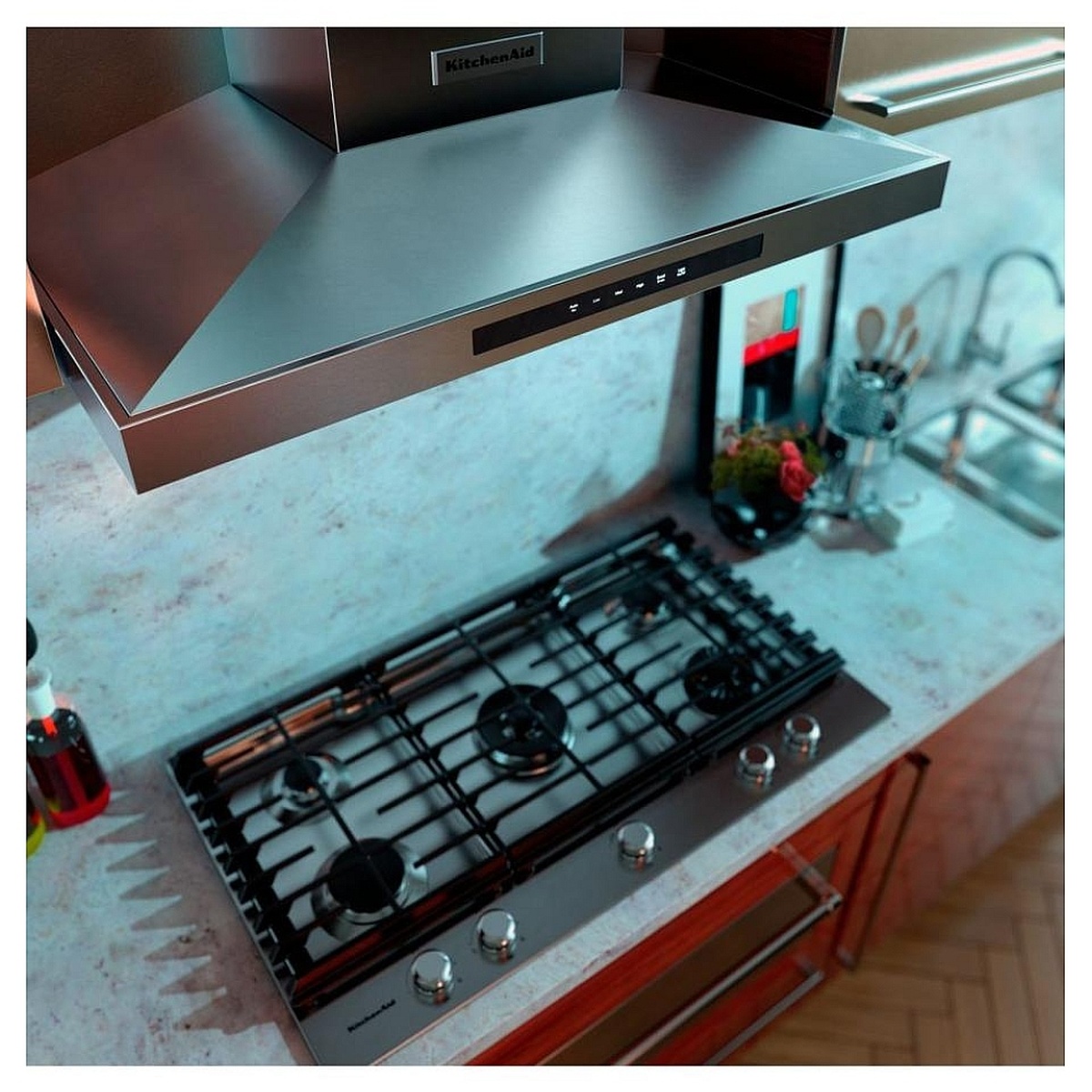 Kitchen scene showing a stainless steel wall-mounted KitchenAid canopy hood installed above a gas cooktop