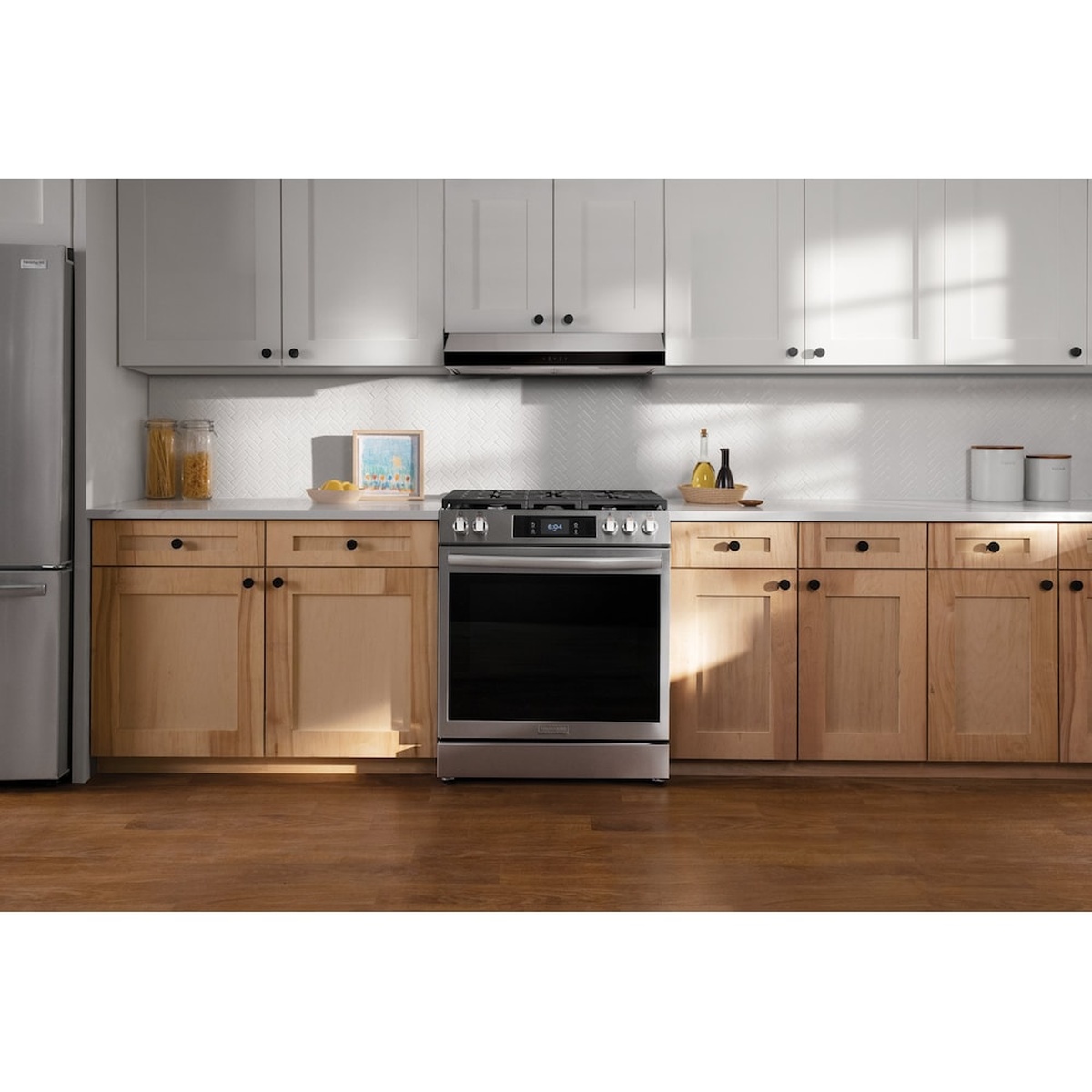 Under-cabinet stainless range hood installed above a freestanding range in a bright modern kitchen