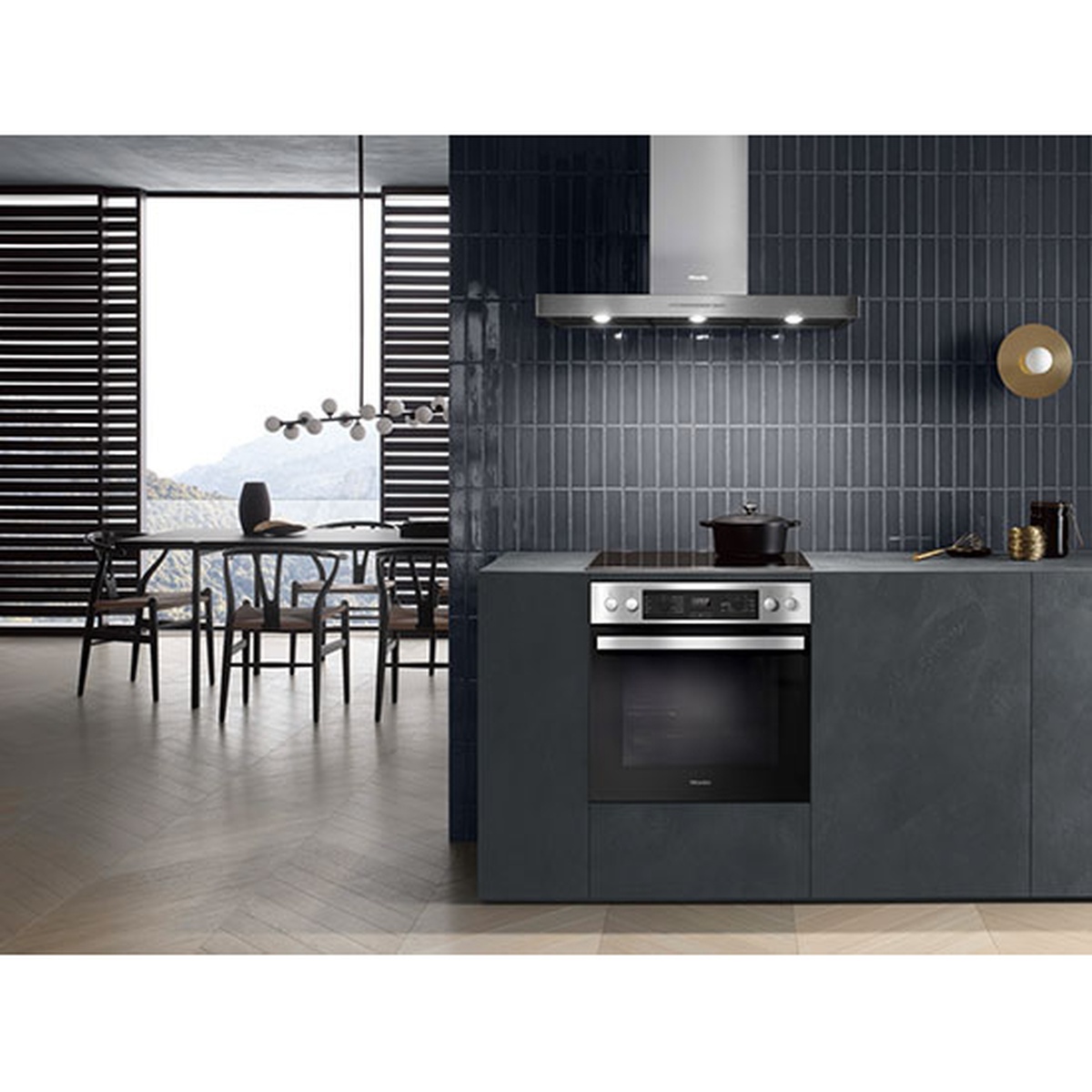 Built-in wall oven installed under a black electric cooktop in a modern kitchen with a stainless wall-mounted range hood