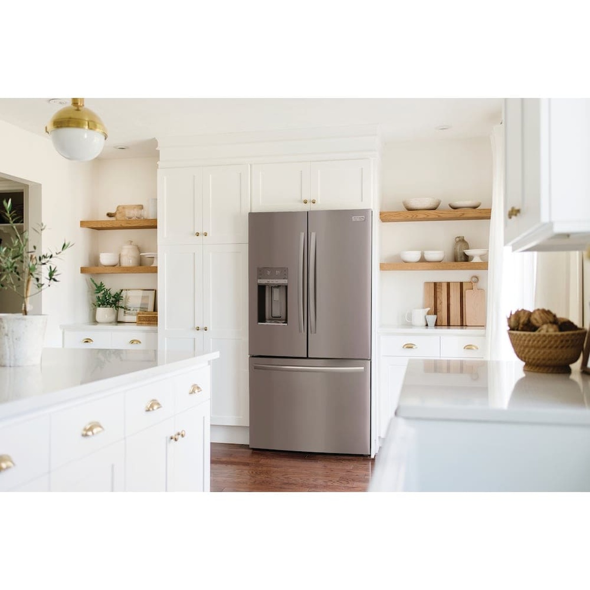 Frigidaire Gallery French door refrigerator in a bright kitchen with an external ice and water dispenser and stainless steel finish