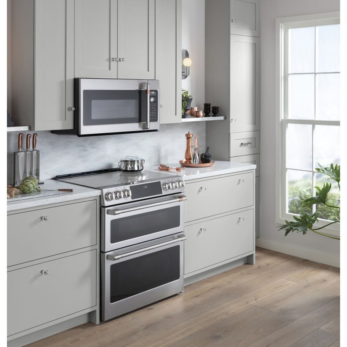 Café slide-in stainless range installed in a modern kitchen with cabinetry and an over-the-range microwave