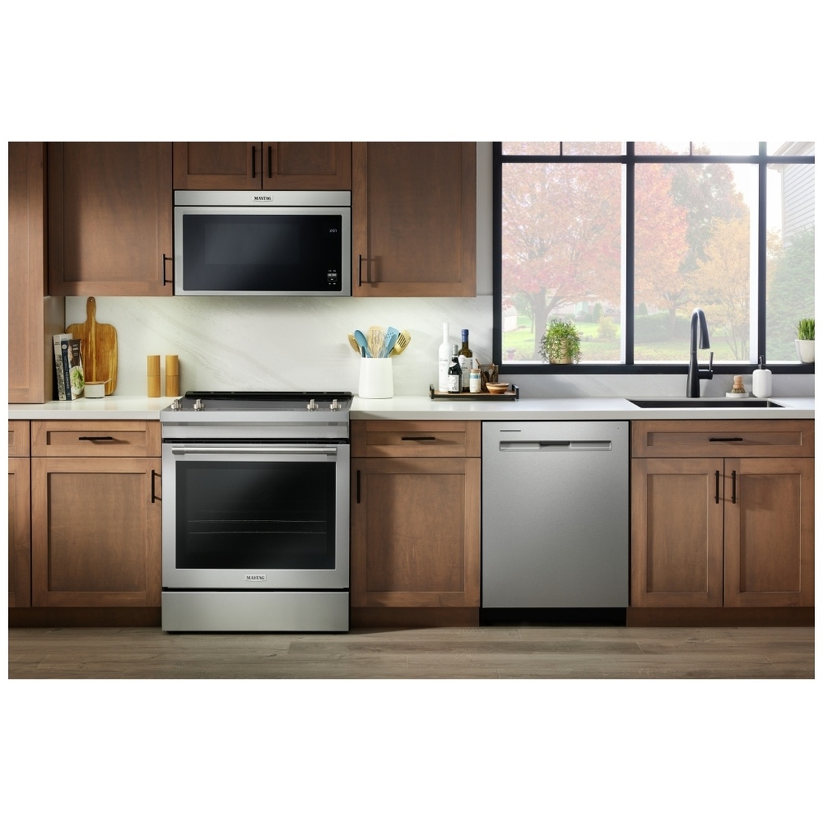 Maytag slide-in electric range installed in a kitchen with wood cabinets and matching stainless appliances