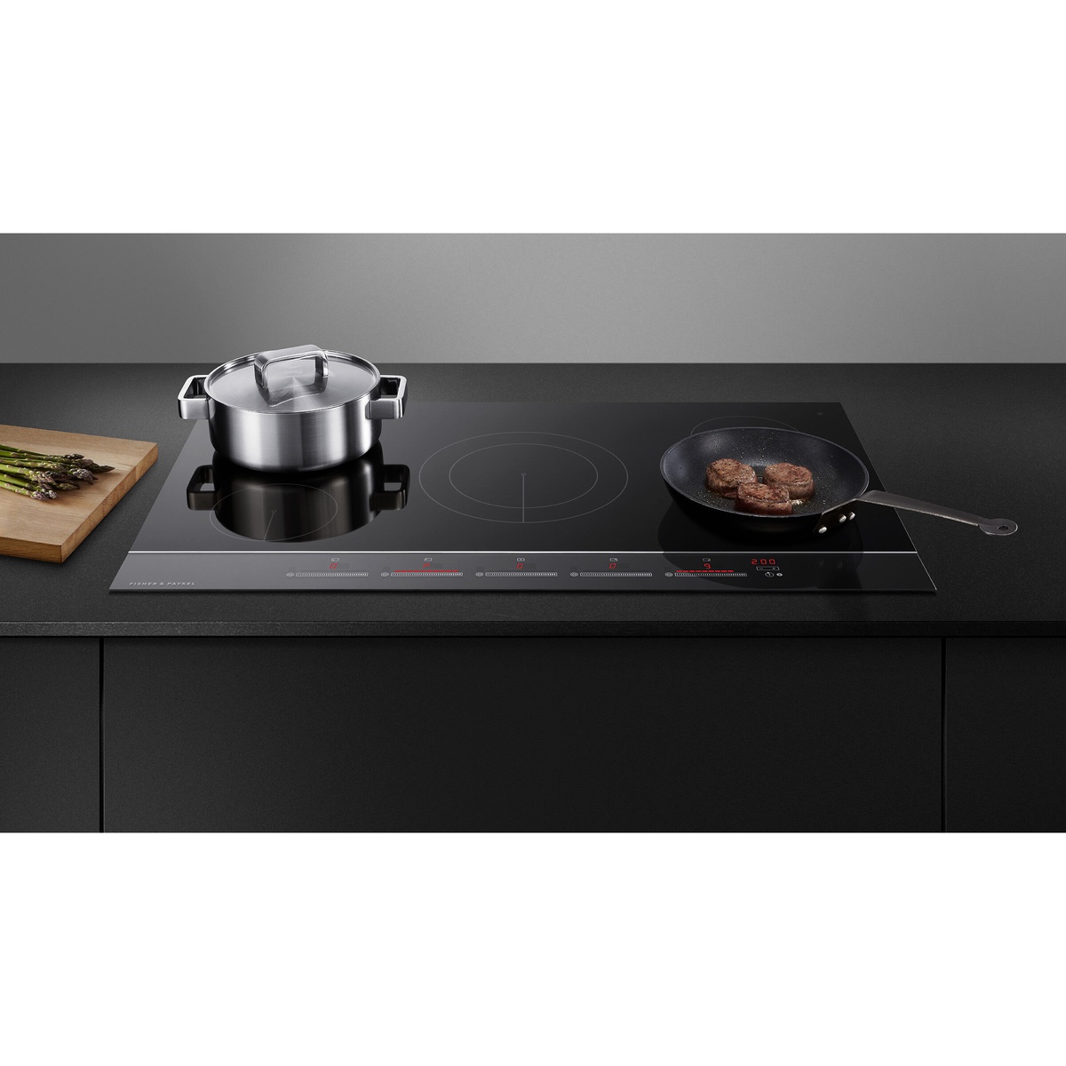 Black glass electric cooktop installed in a dark countertop with cookware on multiple zones and red digital indicators along the front