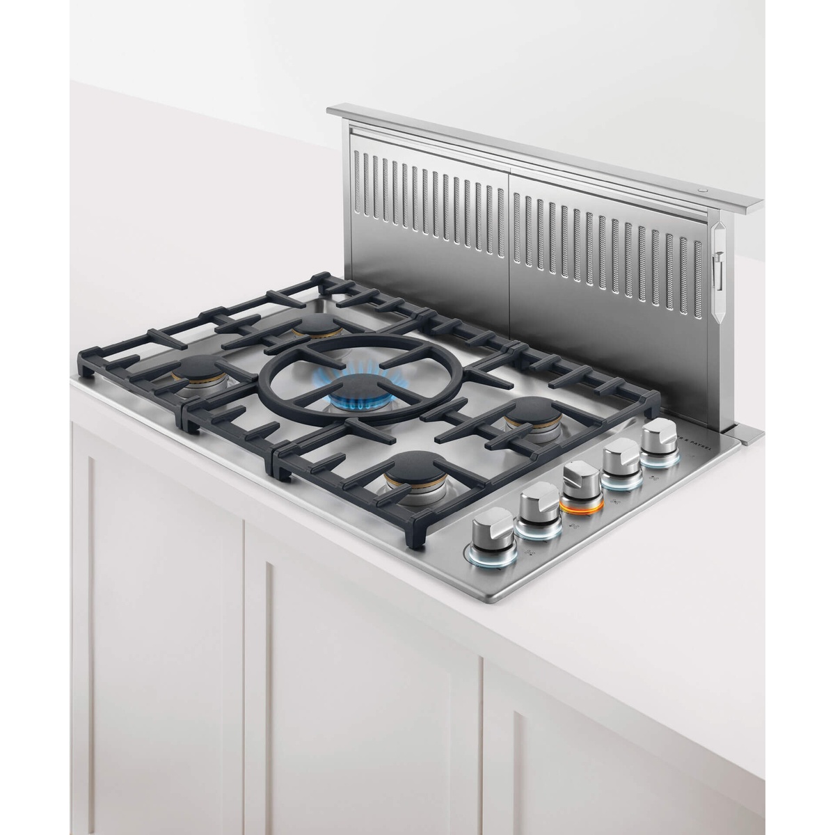 Telescopic downdraft vent raised behind a cooktop with burner grates and control knobs