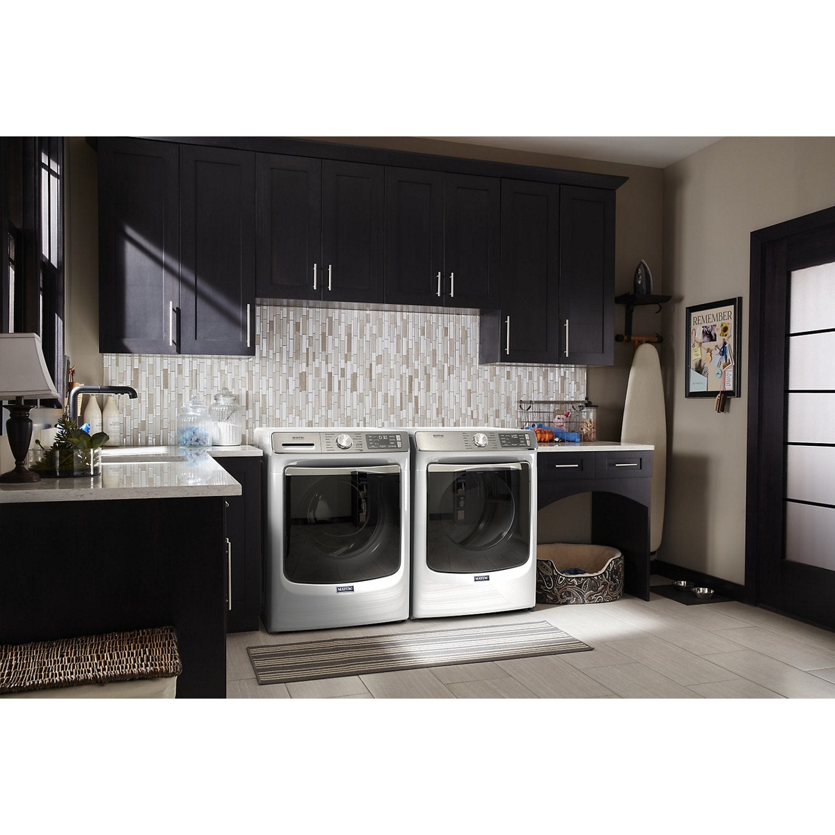 Maytag front-load washer and dryer installed side by side in a modern home laundry room with dark cabinets