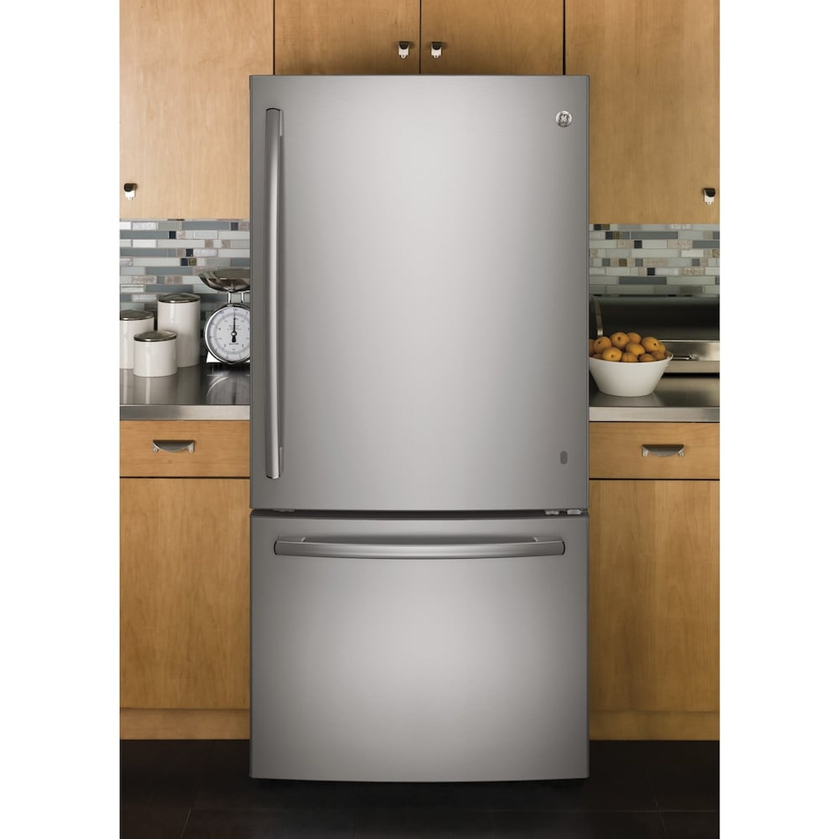 GE stainless bottom-freezer refrigerator installed between kitchen cabinets