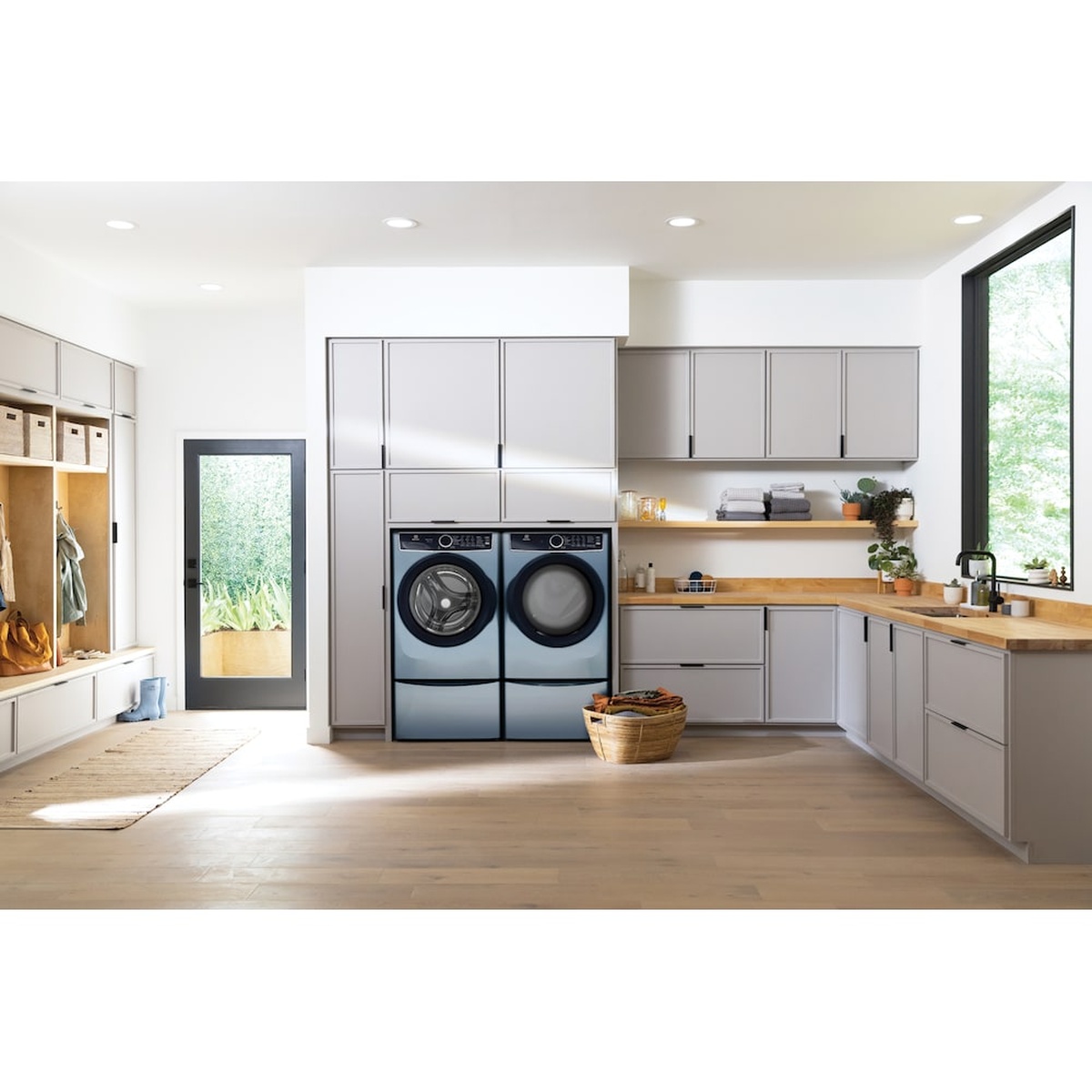 Modern laundry room with matching Electrolux glacier blue front-load washer and dryer installed side by side under cabinetry