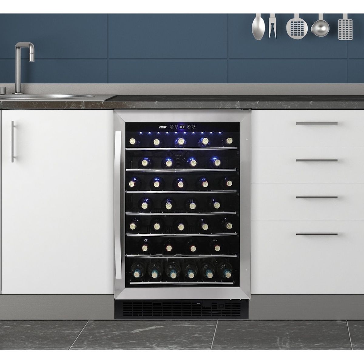 Danby wine cooler installed under a kitchen counter with bottles visible behind the glass door