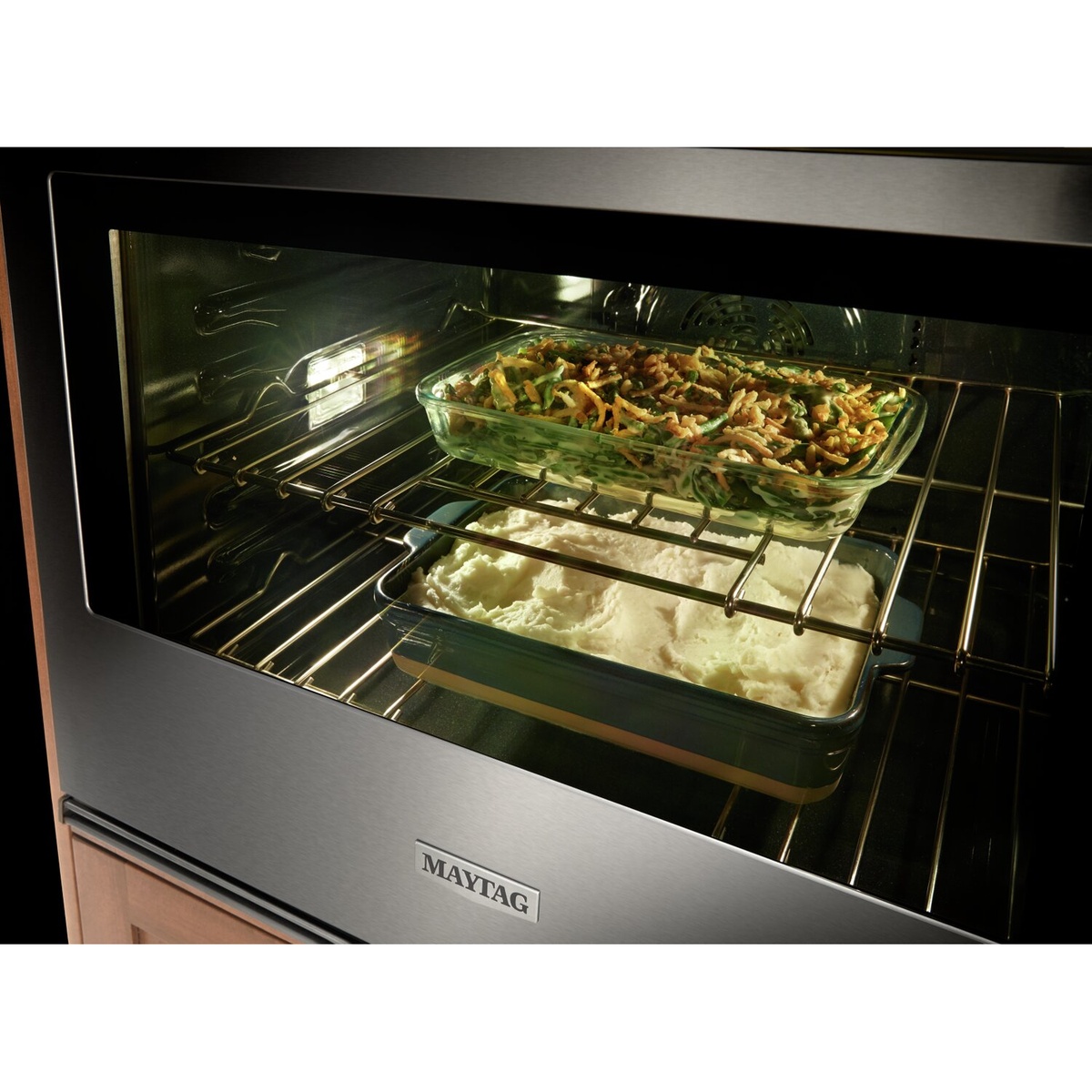 Maytag wall oven interior viewed through the window with dishes baking on two racks