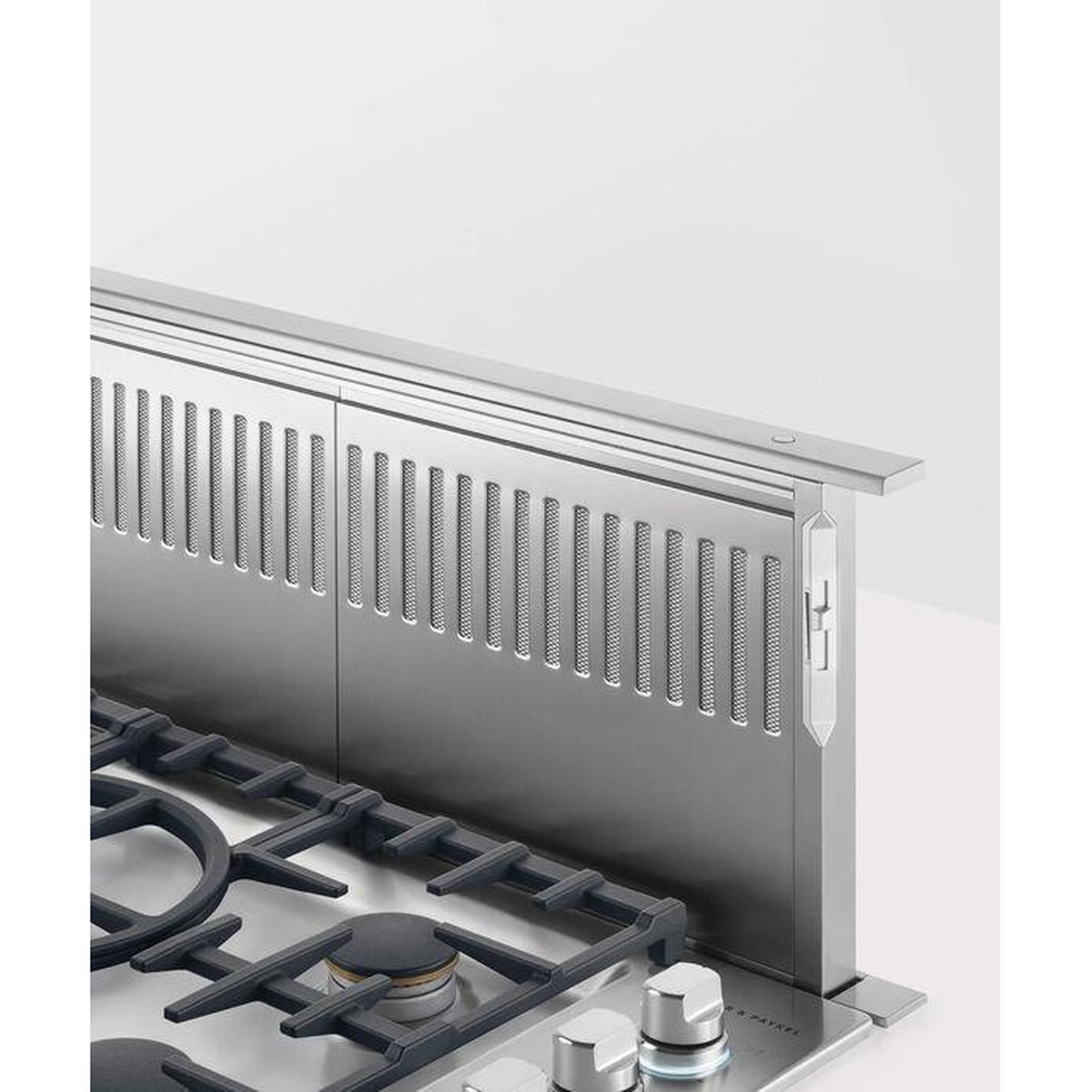 Stainless steel pop-up downdraft vent raised behind a gas cooktop