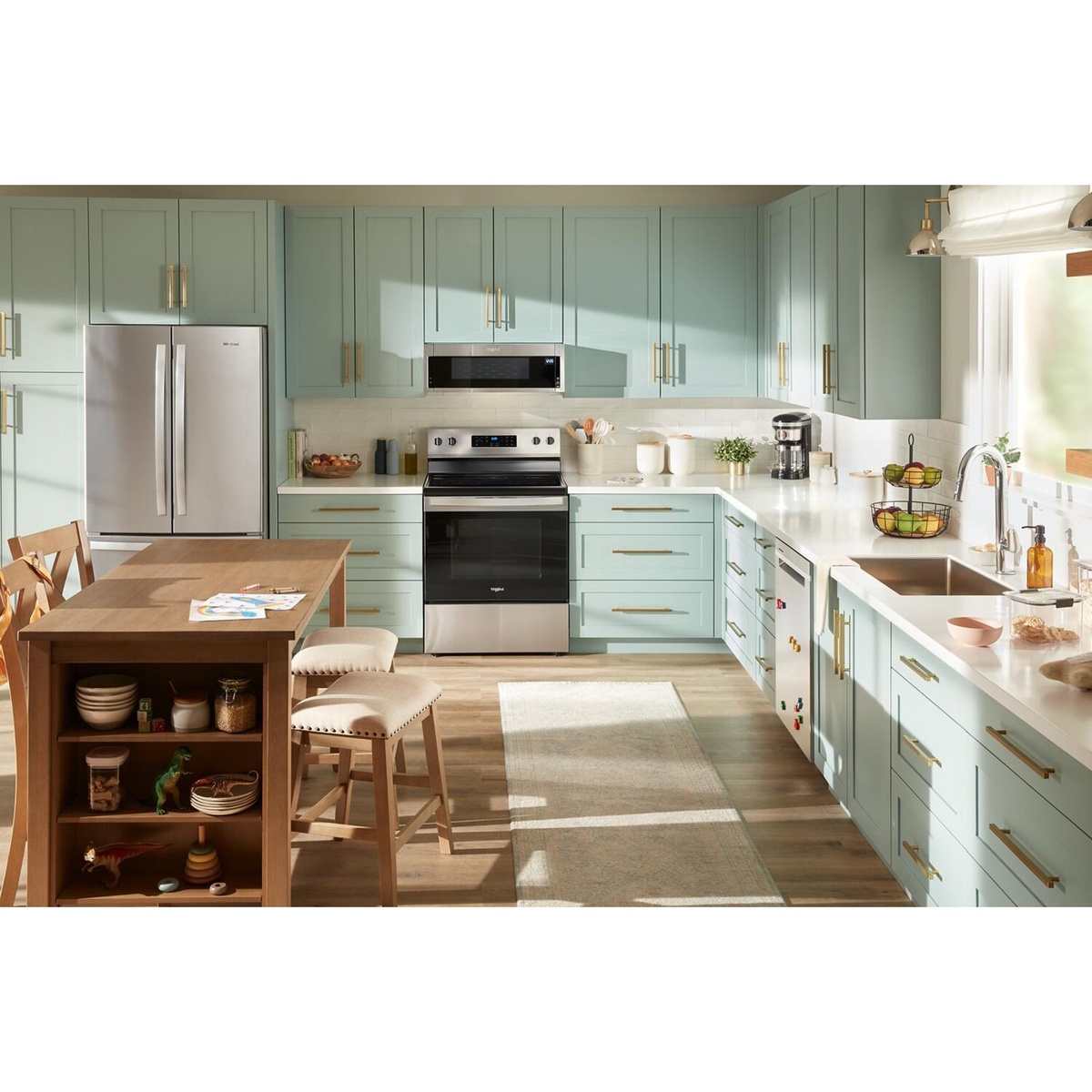 A stainless steel Whirlpool freestanding electric range installed between kitchen cabinets in a bright modern kitchen