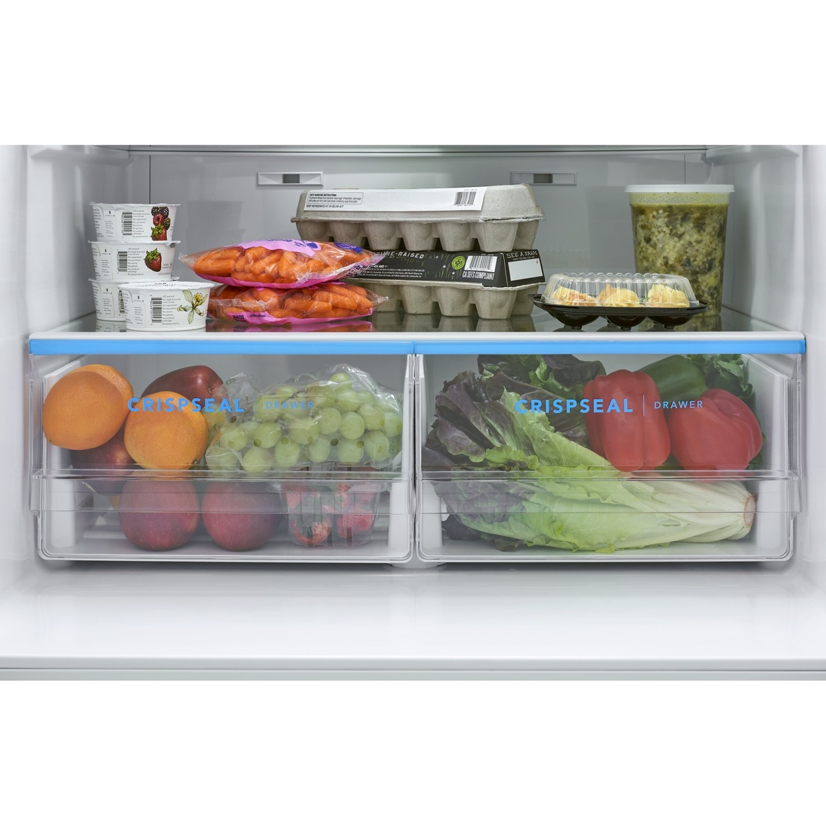 Close-up of two clear CrispSeal crisper drawers with produce inside, shown beneath a full-width glass shelf.