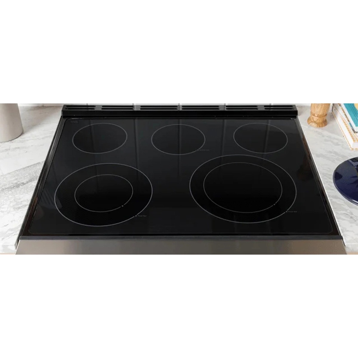 Close-up of the smooth black glass cooktop with five circular cooking zones