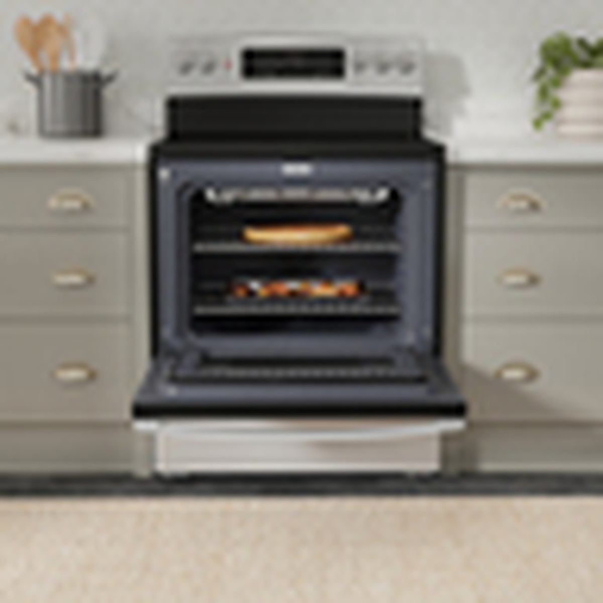 GE stainless steel electric range installed in a kitchen with the oven door open