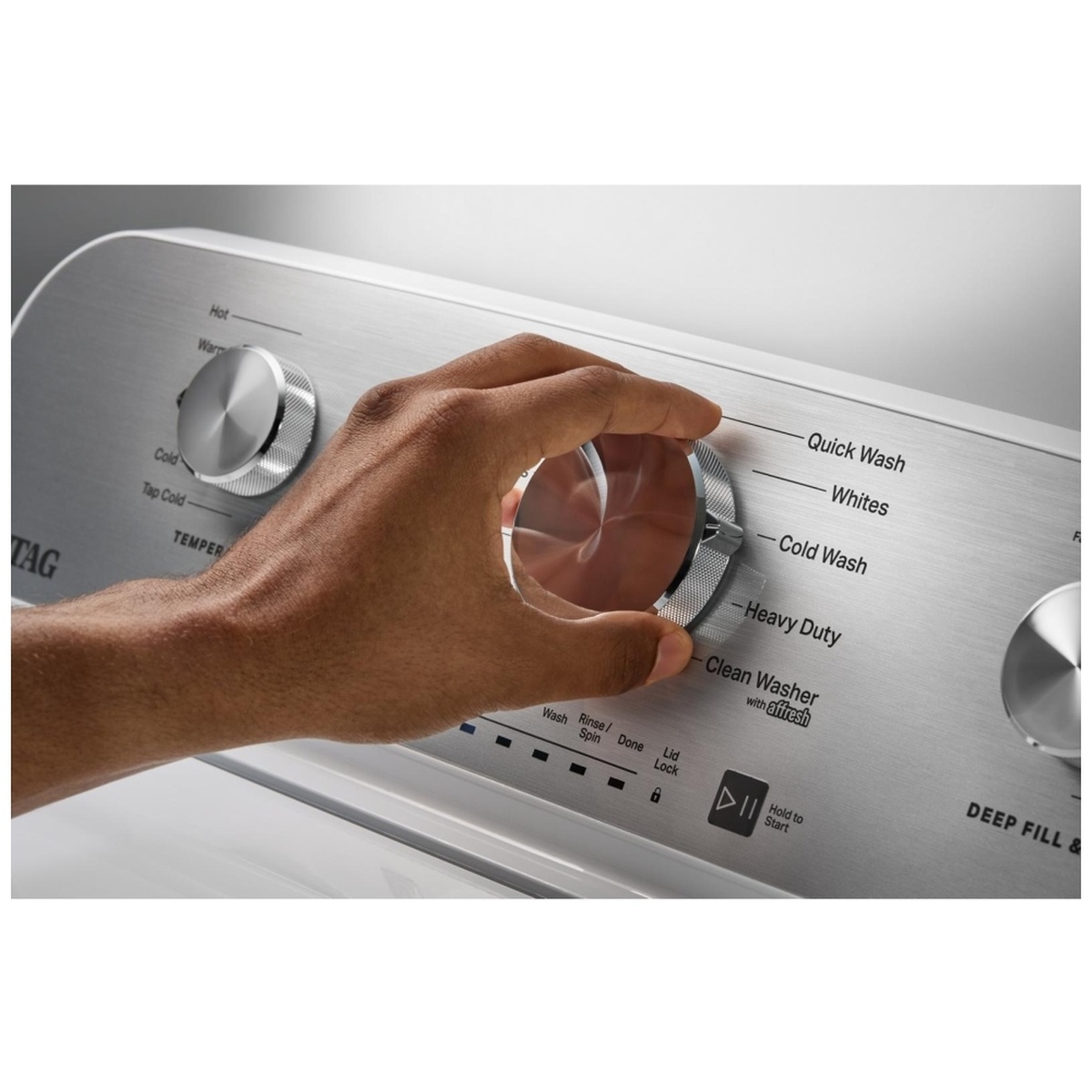 Close-up of the Maytag washer rear control panel with a hand turning the main cycle selection knob