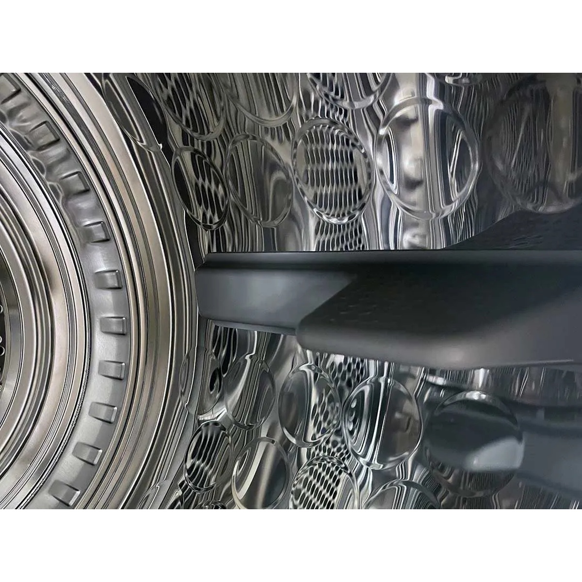 Close-up of the stainless steel dryer drum interior with textured dimples and a drum lifter