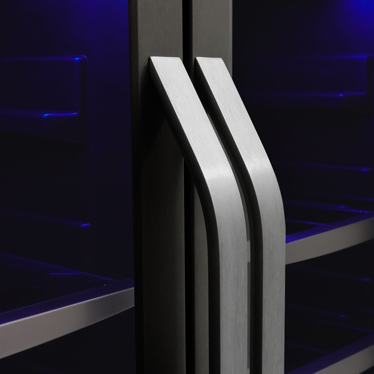 Close-up of brushed metal handles on a stainless steel glass-door beverage center