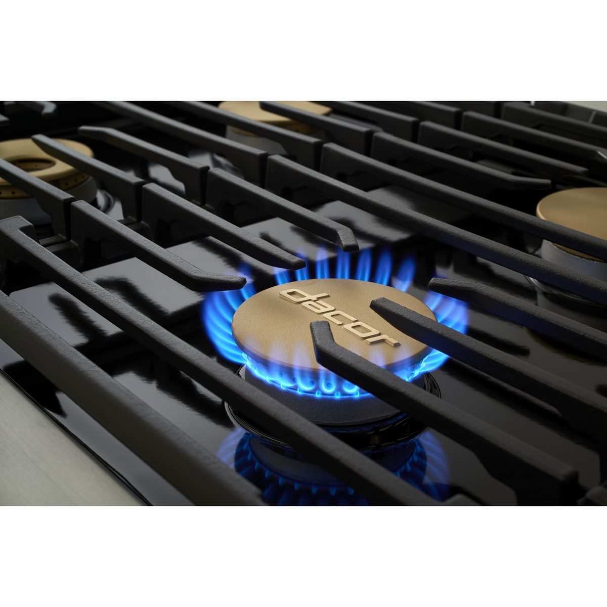 Close-up of a lit gas burner flame beneath cast-iron grate